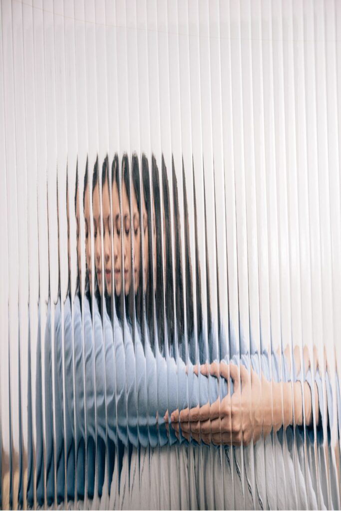 Frau sitzt hinter Glasscheibe 